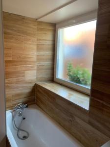 uma banheira na casa de banho com uma janela em T3 neuf - maison alsacienne au calme avec cour privée em Dachstein