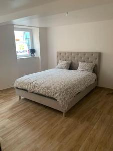 uma cama num quarto com piso em madeira em T3 neuf - maison alsacienne au calme avec cour privée em Dachstein