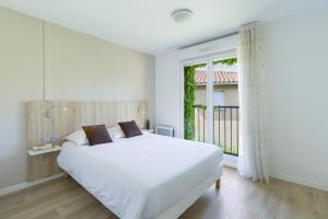 een slaapkamer met een groot wit bed en een raam bij Garden & City Lyon - Marcy in Marcy-lʼÉtoile