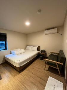 1 dormitorio con 1 cama y 1 silla en Ssangma Motel, en Busan