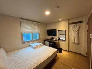 a bedroom with a bed and a dress hanging on the wall at Ssangma Motel in Busan