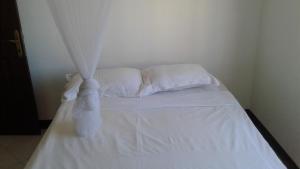 een wit bed met witte lakens en kussens bij DINO 4 in Trou aux Biches