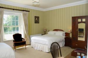 um quarto com uma cama, uma cadeira e uma janela em Cannaway House B&B em Macroom