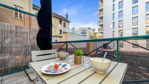 une table avec une assiette de nourriture sur un balcon dans l'établissement HOMEY HELSINKI - Hyper centre - Proche Genève - Terrasse privée - Wifi & Netflix, à Annemasse