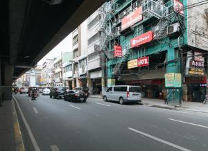 RedDoorz @ Riches Holiday Hotel Avenida في مانيلا: شارع المدينة فيه سيارات تقف على جانب مبنى