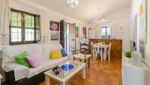 Casa Fuentezuelas Sayalonga by Ruralidays في Sayalonga: غرفة معيشة مع أريكة بيضاء وطاولة