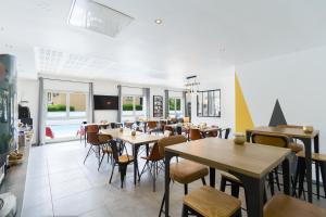 a restaurant with tables and chairs and windows at Garden & City Lyon - Lissieu in Lissieu