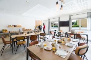 une salle à manger avec des tables et des chaises ainsi qu'une cuisine dans l'établissement Garden & City Lyon - Lissieu, à Lissieu