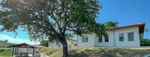 una casa con un árbol delante de ella en Guest Houses Kapatovo / Къщи за гости КАПАТОВО, 