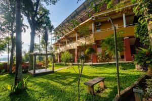 a park in front of a building with a bench at Karapuzha Village Resort in Wayanad