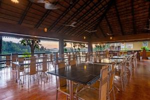 a dining room with tables and chairs and windows at Karapuzha Village Resort in Wayanad