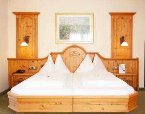 a bedroom with a wooden bed with white sheets at Hotel Garni Alpenland in Altenmarkt im Pongau +43 photos