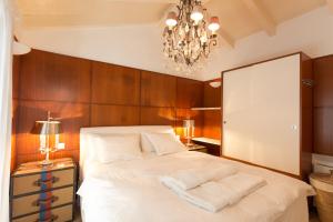 a bedroom with a large white bed with a chandelier at PAVI APARTMENTS Life Style House with private pool in Kornić