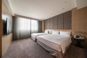 a hotel room with two beds and a television at Taipung Suites in Anping