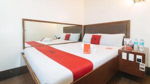 RedDoorz @ Riches Holiday Hotel Avenida في مانيلا: غرفة نوم بسريرين بملاءات حمراء وبيضاء