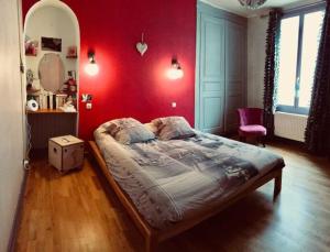 ein Schlafzimmer mit einem Bett und einer roten Wand in der Unterkunft Superbe maison de caractère, de 1 à 9 couchages in Sainte-Maure-de-Touraine