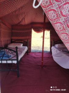 a small room with two beds and a window at SandGlass Camp in Badīyah