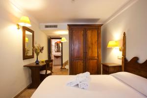 a bedroom with a bed and a desk and a mirror at Hotel Cala Sant Vicenç - Adults Only in Cala de Sant Vicenc