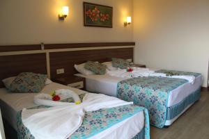 ein Hotelzimmer mit 3 Betten mit Blumen darauf in der Unterkunft Side West Park Hotel in Side