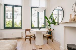 een woonkamer met een tafel en stoelen en een bed bij Quartier Le Sud in Antwerpen