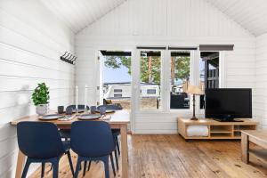a dining room with a table and chairs and a tv at Topcamp Onsakervika - Tyrifjorden in Svensrud