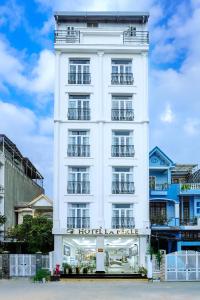a white hotel building with a sign on it at Hotel La Perle in Hue