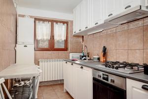 a kitchen with white cabinets and a stove top oven at Coolis Apartments Șirul Livezii in Braşov