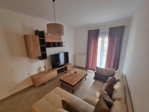 een woonkamer met een bank en een tv bij AGORA luxury APARTMENT 1 in Loutraki