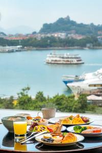 a table with plates of food and a view of the water at Hotel Indigo Xiamen Harbour, an IHG Hotel in Xiamen