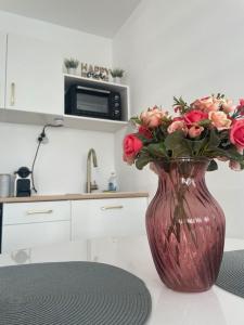 eine rote Vase mit rosa Rosen in der Küche in der Unterkunft Superbe appartement au cœur de La Défense in Courbevoie
