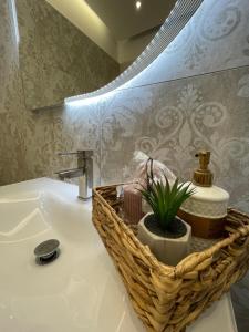 een badkamer met een wastafel en een mand met een plant bij AGORA luxury APARTMENT 1 in Loutraki