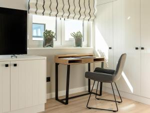 Habitación con escritorio, silla y TV. en Meine Schöne 21a, en Fuhlendorf