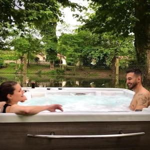 un hombre y una mujer sentados en un jacuzzi en Le Mill, en Meilhan