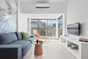 uma sala de estar com um sofá e uma televisão em Design Apartments em Tel Aviv