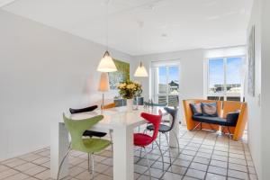 ein Wohnzimmer mit einem weißen Tisch und bunten Stühlen in der Unterkunft Lovely holiday home in Josefines Have 43 in Løkken
