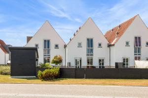 eine Reihe weißer Häuser mit einem schwarzen Zaun in der Unterkunft Lovely holiday home in Josefines Have 43 in Løkken
