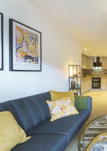 a living room with a blue couch and a kitchen at Euphorbia - 1 Bedroom Luxury Apartment by Mint Stays in Bristol