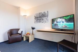 a room with a tv and a chair and a desk at Aarau West Swiss Quality Hotel in Oberentfelden