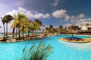una piscina in un resort con palme e sedie di Archipel - Cocon d'une architecte en Guadeloupe a Saint-François