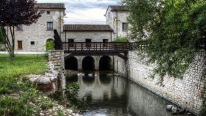 a bridge over a river in front of a building at Albergo Diffuso La Piana dei Mulini in Colledanchise