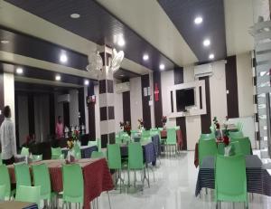 uma sala de jantar com cadeiras e mesas verdes e uma televisão em Hotel Glory Grand, Rajgir em Rajgir