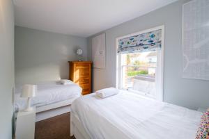 a white bedroom with two beds and a window at Sleepers Cottage in Aldeburgh