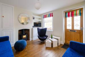 a living room with blue chairs and a fireplace at Sleepers Cottage in Aldeburgh