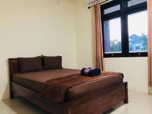 Bett in einem Zimmer mit einem großen Fenster in der Unterkunft Calliandra Homestay in Banyuwangi