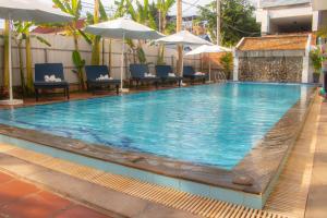 a pool with chairs and umbrellas at a hotel at The Blanc Residence in Siem Reap