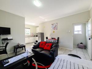sala de estar con sofá de cuero negro y almohadas rojas en House of Grace Apt, en East London