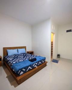 Schlafzimmer mit einem Bett mit blauer Decke in der Unterkunft Calliandra Homestay in Banyuwangi