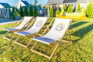 three beach chairs sitting on the grass in a yard at TRZĘSAWISKO in Trzęsacz