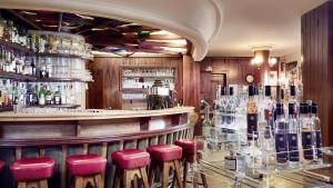 un bar con taburetes rojos y botellas de vino en Loisach Smarthotel by keyone, en Lermoos