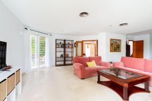 ein Wohnzimmer mit 2 rosa Stühlen und einem Couchtisch in der Unterkunft Holi-Rent Colina Blanca in Camas